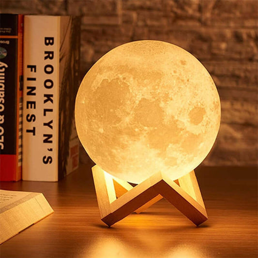 Moon LED lamp on wooden stand glowing on a book shelf